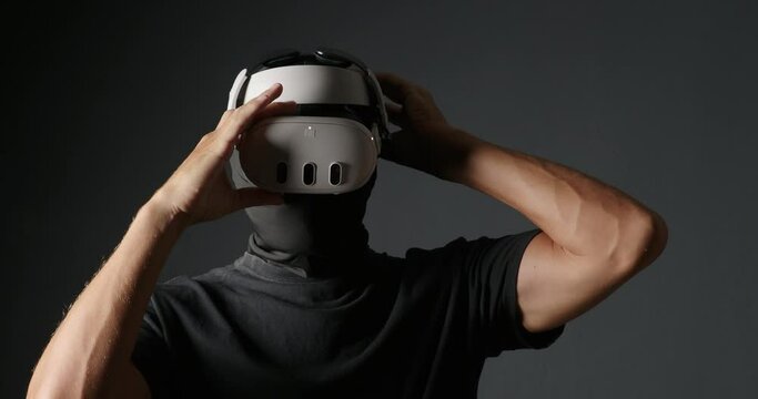Man cheater in black mask puts on virtual reality headset.