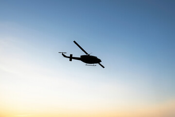Photos of Military Helicopter flying against sunset.Flying a helicopter in the blue sunny sky