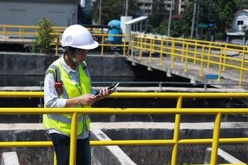 Workers under checking the wastewater treatment pond industry to control the water support...