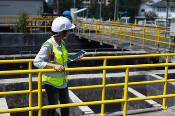 Workers under checking the wastewater treatment pond industry to control the water support industry. Engineer takes water from the wastewater treatment pond to check the quality of the water