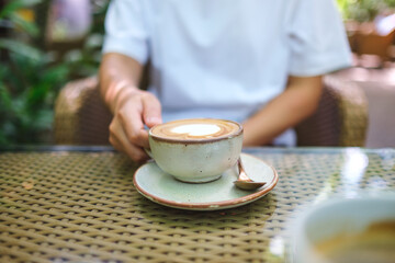 Closeup image of a woman holding and drinking coffee