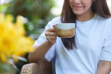 Closeup image of a young woman holding and drinking coffee