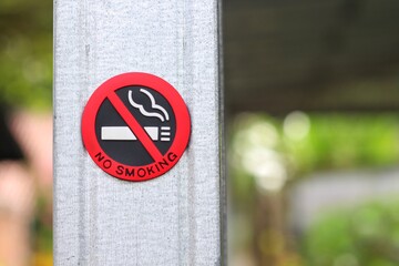 No Smoking sign on the pole in the public park with blur nature background