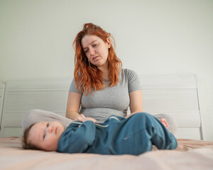 Naklejka premium Woman with postpartum depression sitting on bed next to newborn. 