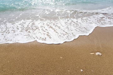 Wave caressing the soft sand of a beach in Alicante.