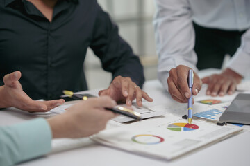 Business meeting showing hands of professionals analyzing charts and discussing reports over a...