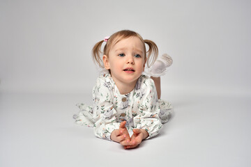 Cute child lying on a white background. Portrait of little girl with blue eyes