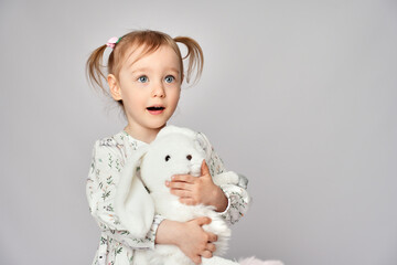 Little girl with white bunny on a white background with copy space. Portrait of beautiful little...