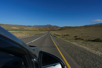 view from the window of the road, blue sky and mountains while driving while traveling in Altai