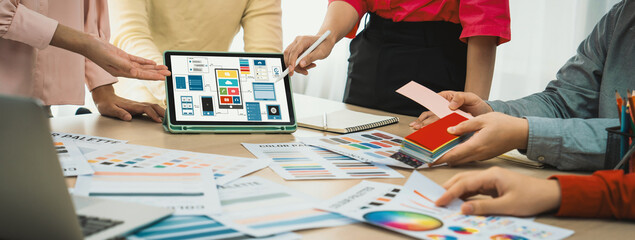Cropped image of interior designer team chooses color from color swatches while tablet displayed UI and UX designs for mobiles app and website. Creative design and business concept. Variegated. © InfiniteFlow