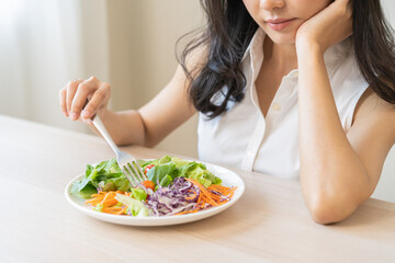 Diet in bored face, unhappy beautiful asian young woman, girl on dieting, holding fork at tomato on salad plate, dislike or tired with eat fresh vegetables. Nutrition of clean, healthy food good taste