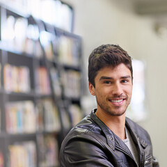 Man, student and portrait in library for education or learning, books for knowledge at university. Male student, campus and smile in study room for information, bright future at college in Chicago