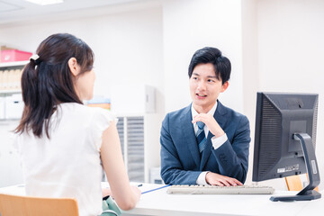 不動産会社のカウンターで相談をする若い女性