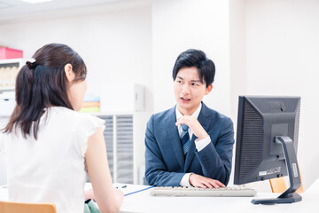 Obraz premium 不動産会社のカウンターで相談をする若い女性