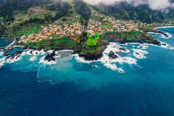 Aerial view of rough ocean with waves, volcanic beach and swiming pool in Seixal, Madeira, Portugal