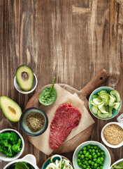 Set of raw ingredients to cooking a healthy plate on wooden table, beef tenderloin, bulgur grains and various vegetables top view, diet food