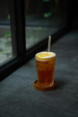 iced lemon tea drink served on transparent glass over small wooden plate on stone tile