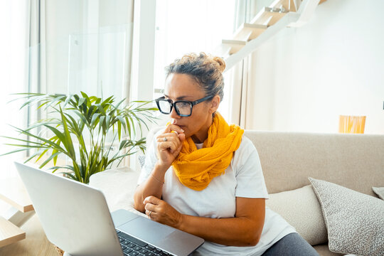 One woman using laptop sitting on sofa in cozy apartment. Window lights in background. Female people enjoying technology in indoor leisure activity reql life. Surfing the net alone browsing web pages