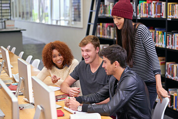 Education, library and happy group of students on computer for exam, learning knowledge and friends research. University, desktop and team of people studying together, discussion or laugh in college