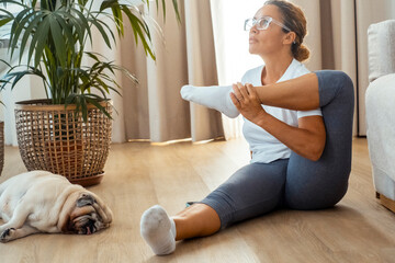 Middle age lady doing home workout in living room with sleeping dog near her. Cozy and healthy...