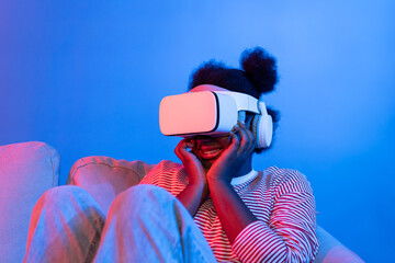 Young African watching scary movie through VR glasses feeling scared in fantastic 3D horror film...