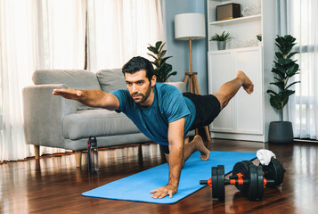 Flexible and dexterity man in sportswear doing yoga position in meditation posture on exercising...