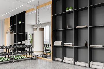 Stylish sport room interior with dumbbell rack and punching bag, shelf with mat