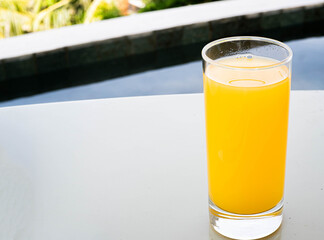 Glass of orange juice by the pool