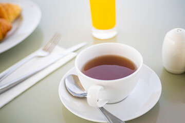 Breakfast table with tea, orange juice, and croissant