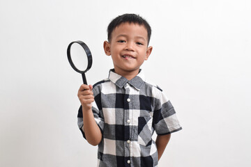 Image of Asian child posing using a magnifying glass and looking through the magnifying glass,...