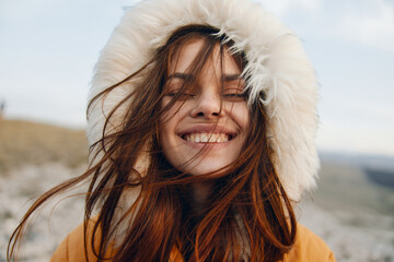 Woman smiling in fur coat on sunny day in windy fashion photoshoot on urban street