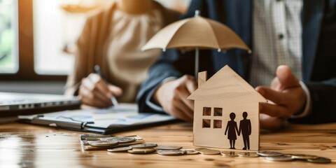 Insurance agent showcasing services to promote and sell insurance policies. An insurance agent's hands protecting a model house and a family of wooden dolls.