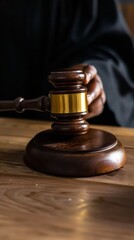 A judge sits at a wooden table, holding a wooden gavel in one hand