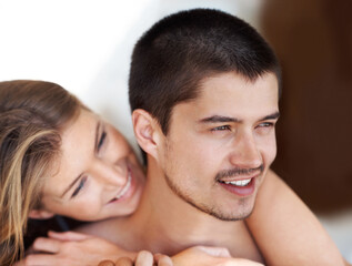 Fototapeta premium Romance, woman and man in bedroom with hug, smile and relax together for holiday fun in home. Embrace, love and happy couple in hotel room on weekend morning with wake up, care and rest in apartment