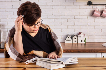 Thoughtful woman reading a book and enjoying a quiet moment in a cozy kitchen setting