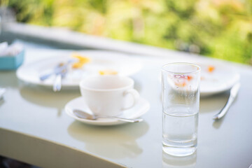 Table with glass of water, coffee cup, and plates with leftover food