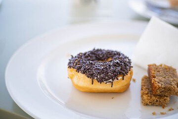 Chocolate-sprinkled donut on a white plate