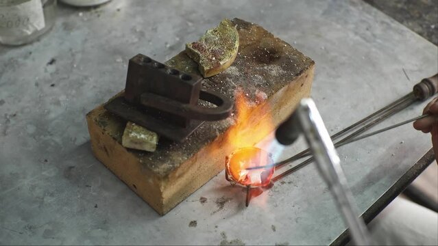 Heating with a flame jet of a metal billet of a silver ring. The work of a jeweler in the workshop