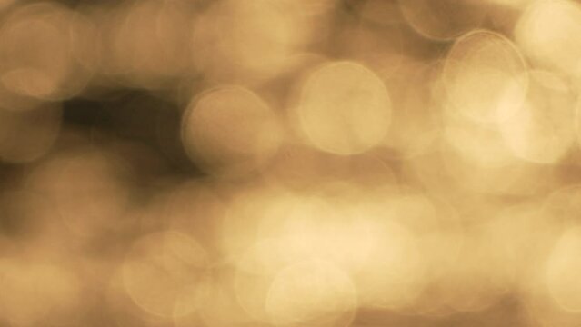 Blurred golden sea at sunset with shifting focus and bokeh effect. Sun reflects and sparkles on waves, illuminating golden sea. Holiday recreation concept. Abstract nautical summer ocean sunset nature