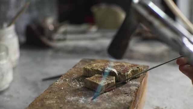 Heating with a flame jet of a metal billet of a silver ring. The work of a jeweler in the workshop