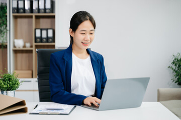 Asian woman using laptop and tablet while sitting at her working place.