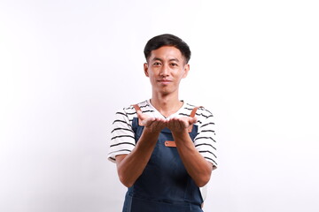 Young asian bartender man wearing apron showing his empty palm to the front, holding something...