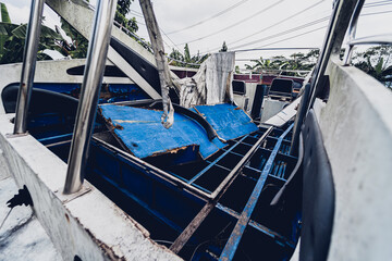 Old and rusty motor boats on a landfill surrounded by tropical forest