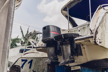 Old and rusty motor boats on a landfill surrounded by tropical forest