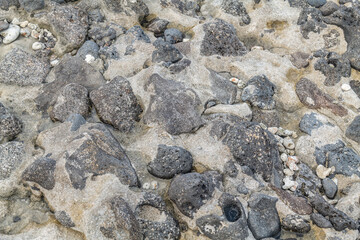 Beachrock is a friable to well-cemented sedimentary rock that consists of a variable mixture of basalt gravel , sand , and silt-sized sediment. fragments of coral and shells . Geology 
