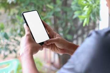 Man hands holding smart phone with blank copy space screen for your text message or information content, reading text message on cell telephone during in urban setting.
