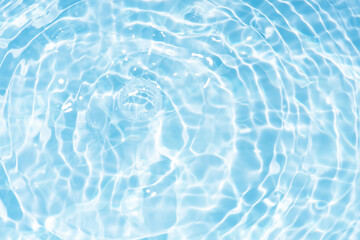 Blue water with ripples on the surface. Defocus blurred transparent blue colored clear calm water surface texture with splashes and bubbles. Water waves with shining pattern texture background.