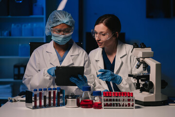 Team of biochemical research scientists working with a microscope for vaccine development.