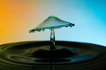Water drops forming a mushroom against a colorful backdrop.