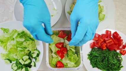 Chef make fresh vegetable salad close up top down view. Woman cook hands put ingredients slices in disposable container. Cooking, preparing in professional restaurant. Healthy food delivery. 4K shot